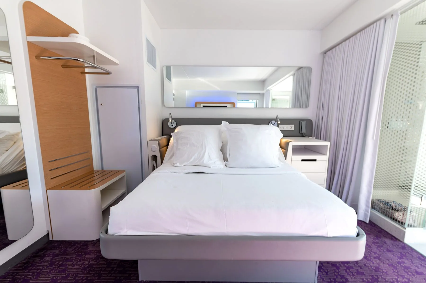 A neatly made bed with surrounding furniture and curtains