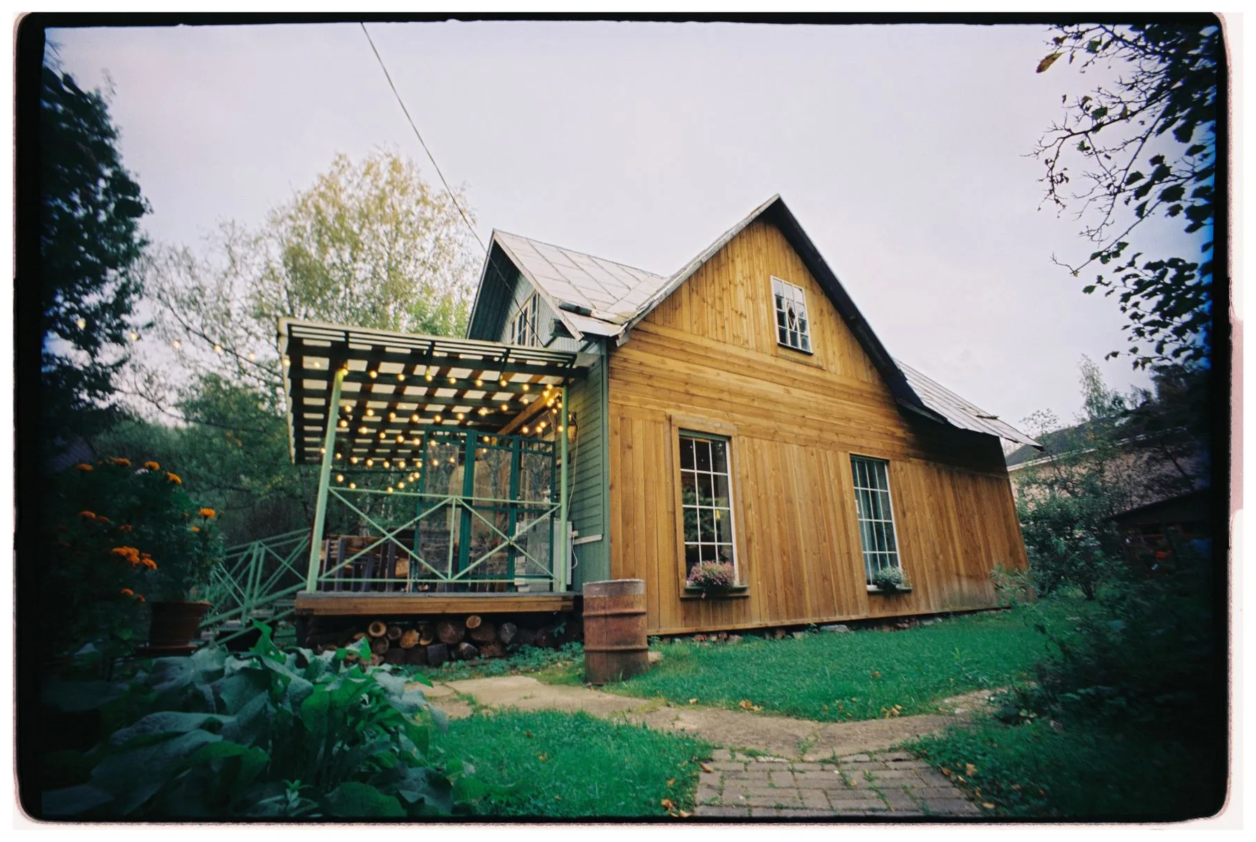 A timber-clad house with a sheltered porch and garden